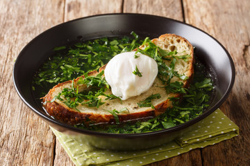 Summer Acorda Soup with cilantro, garlic, homemade bread and poached egg close-up in a plate....