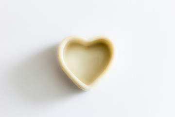 The washed out figurine of heart is on a white background under a sunlight
