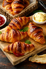 Freshly baked croissants with butter, strawberry jam and tea for breakfast or brunch