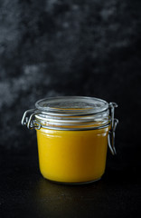 Glass jar with the lemon curd on the dark background