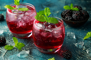 Refreshing Blackberry cocktail with ice and mint on rustic background