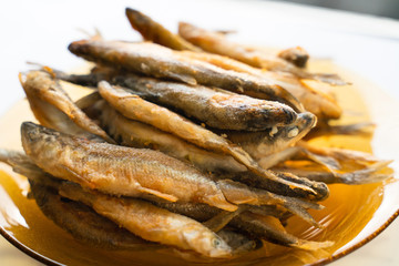 smelt fried in flour on a yellow glass plate close up