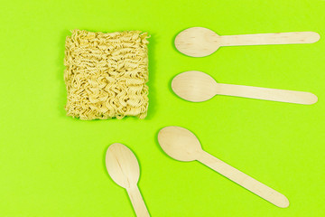 Instant pasta on a colored background with disposable wooden eco cutlery.