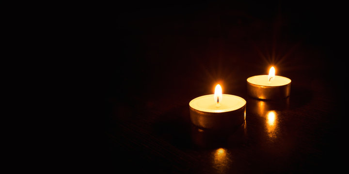 Two burning candles on a black background. Banner with copy space.