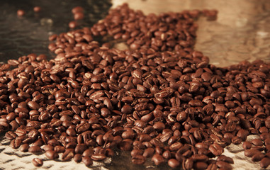 Coffee beans poured from a black bag ona glass  table