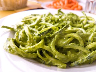 Raw spaghetti of zucchini with pesto green sauce tipical revisited fusion pasta italian cuisine dish for vegan choice