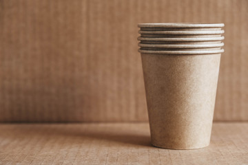Disposable paper cups on kraft paper background. Eco friendly disposable tableware. Zero waste...