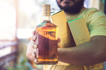 Closeup of man hand holding whisky liquor bottle during Covid-19  lockdown 