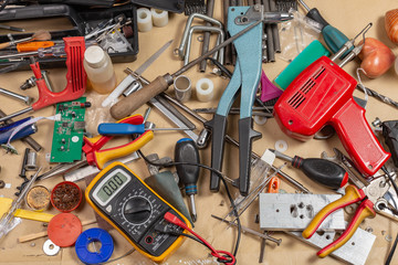 A lot of tool and material are randomly scattered on the desktop.