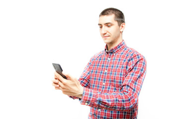 Young man in a plaid shirt with a smartphone on a white background. The guy looks at the smartphone and holds it in front of  him