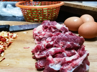 Cooking ingredients name Stir-fried basil beef with a fried egg. And chopped fresh chilies with garlic Place on a wooden chopping board with a knife. Holy basil leaves in an orange basket