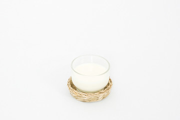 a glass of milk with rattan coaster on the white background.