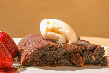 Brownie with vanilla ice cream and red strawberry. Brownie include nuts