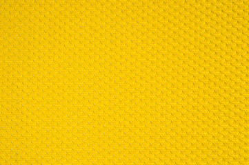 Synthetic yellow perforated stretch fabric, photographed close-up.