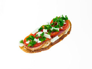 Toast with feta cheese, tartar sauce, parsley greens, tomatoes and smoked meat on dark grain bread on white isolated background.
