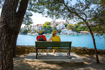 Two Women sitting on a bench overlooking a beautiful mediterranean harbour on a sunny summer day