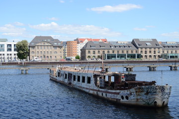 Naklejka premium Ein verlassenes Schiff mitten auf der Spree. Ein Blick aus Kreuzberg nach Ostberlin 2020. Die Zeiten haben sich geändert und jetzt sorgt dieser Ort für Entspannung und Abwechslung. 