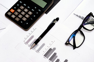 Top view Close up of business working data document graph chart report marketing research calculator pen glasses documents on the table, office workplace.Business office concept.