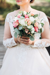 bride in a white dress with a chic bouquet in her hands. Luxury wedding bouquet. The girl is holding flowers - roses, peonies, archedes.