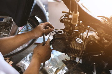 motor style. mechanic fixing motorcycle with soft-focus and over light in the background