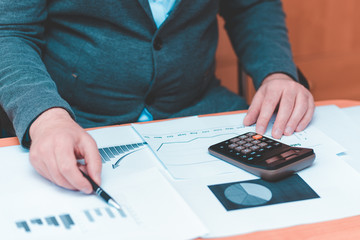 Side view of Cropped picture businessman working on desk office  financial graph with using a calculator to calculate the numbers,accounting investment and finance concept.