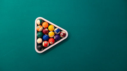 Sports game of billiards on a green cloth. Multi coloured billiard balls in the form of a triangle...
