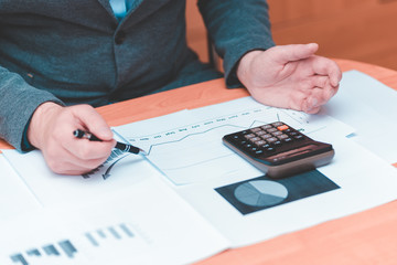 Side view of Cropped picture businessman working on desk office  financial graph with using a calculator to calculate the numbers,accounting investment and finance concept.
