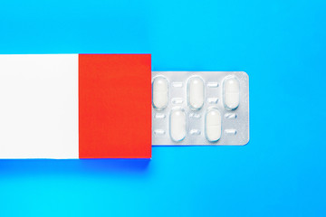 blister pack with pills in a red-white box on a blue background. copy space. flat lay