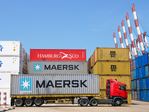 Shipping Containers in various colors stacked at a holding platform.