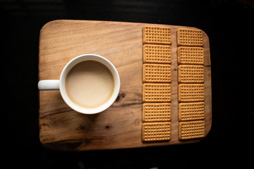 Hot beverage with 12 biscuits on a wooden board