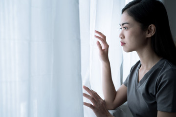Asian woman looked out of the window, She is lonely and she wants to go outside the house, Depression.