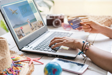 Young women planning summer vacation trip and searching information or booking hotel and using credit card on laptop, Travel concept
