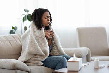 Sick Black Woman Suffering From Flu At Home, Drinking Tea And Resting