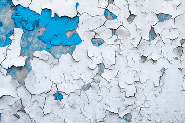 Peeling paint on a concrete wall. Blue and white painted abstract background, grunge cracked surface, pattern texture.