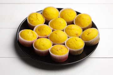 Cupcakes on black plate on white wooden table. Pumpkin muffins. Homemade bakery