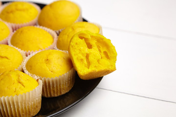 Cupcakes on black plate on white wooden table. Halved pumpkin muffin. Homemade bakery