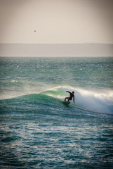 Surfer on a turquoise wave, evening light