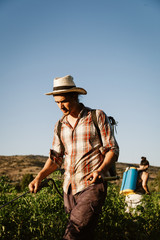 Fototapeta premium Young farmer spraying organic fertilizer with manual pump tank