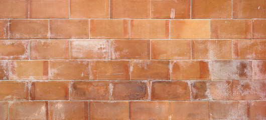 dirty wall background texture with tiles or bricks and irregular tones of orange