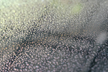 Water sticks on the car rear windscreen after washing the car. Water droplets on the glass. Abstract and Blur water droplets background.