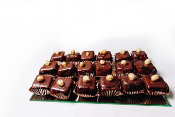 Delicious chocolate cupcakes with chocolate icing and sprinkled gold sparkles on white porcelain plate on isolated white background. Mockup for your design. Close-up. Place for text.