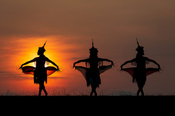 The black silhouette of three Manohra actors dancing in the park in the evening. Manohra performance is a folk dance that has a long history in southern Thailand.