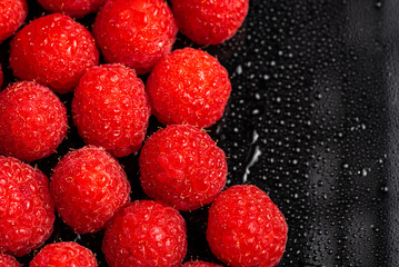 Fresh sweet raspberries close up on black background. Blured background macro. Copy space