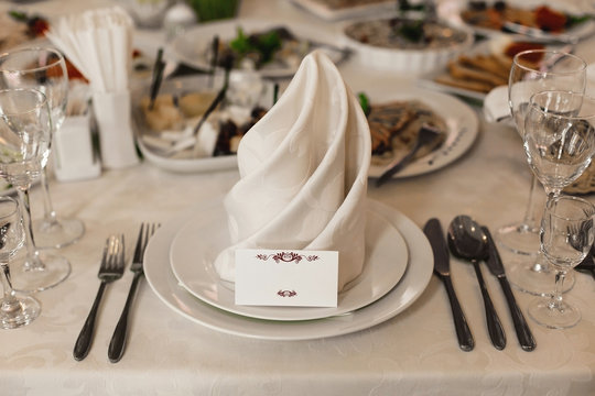 Wedding table serving. Wedding banquet. Beautiful festive table decorated with bouquet of flowers, black plate with card of name guest and cutlery. Top view