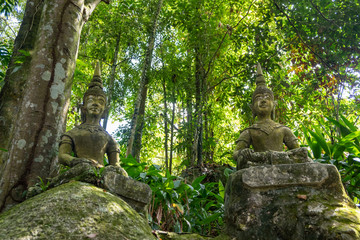 Ancient stone statues in Secret Buddhism Magic Garden, Koh Samui, Thailand. A place for relaxation and meditation. Secret Buddha Garden