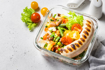 Grilled sausage and steamed vegetables in glass bowl. Top view, space for text.