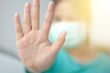 Asian woman showing hand stop gesture standing outdoor.