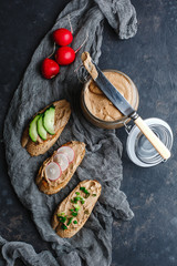 Fresh homemade chicken liver pate with herbs. Bread bruschetta with liver pate with onion, cucumber and radish. Top view, side view on a dark background. space for text.