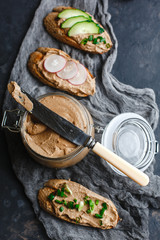 Fresh homemade chicken liver pate with herbs. Bread bruschetta with liver pate with onion, cucumber and radish. Top view, side view on a dark background. space for text.