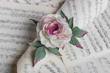 Artificial rose on music notes background